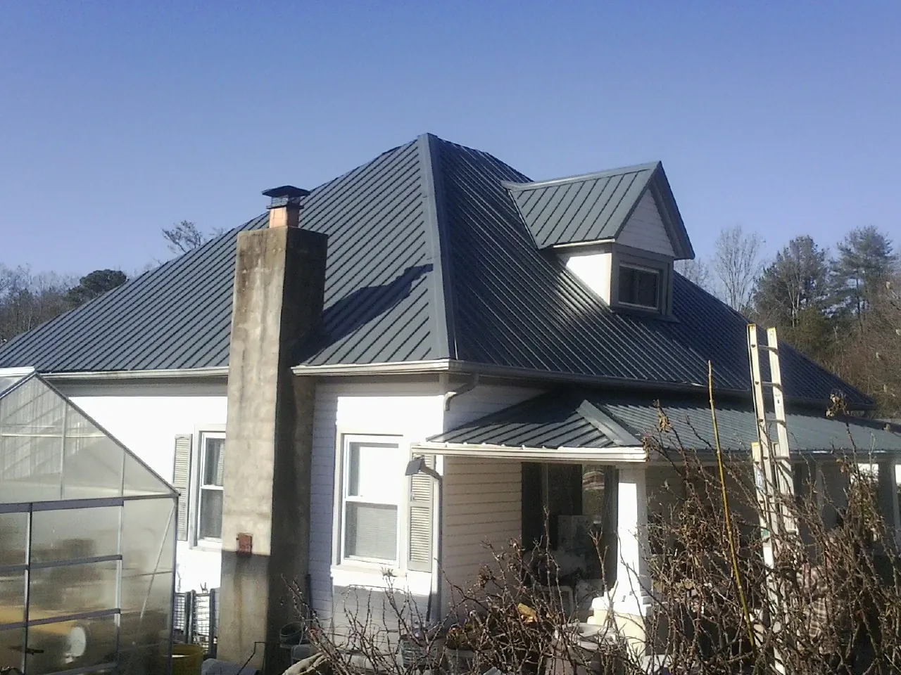 Dark blue standing seam metal roof on a white farmhouse with dormer — Slate & Tile Roof Repair by Roofing Brothers in Pelion