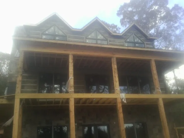 Dormers and porch framing on a large log home under construction — Roof Coating work by our crew in Pelion