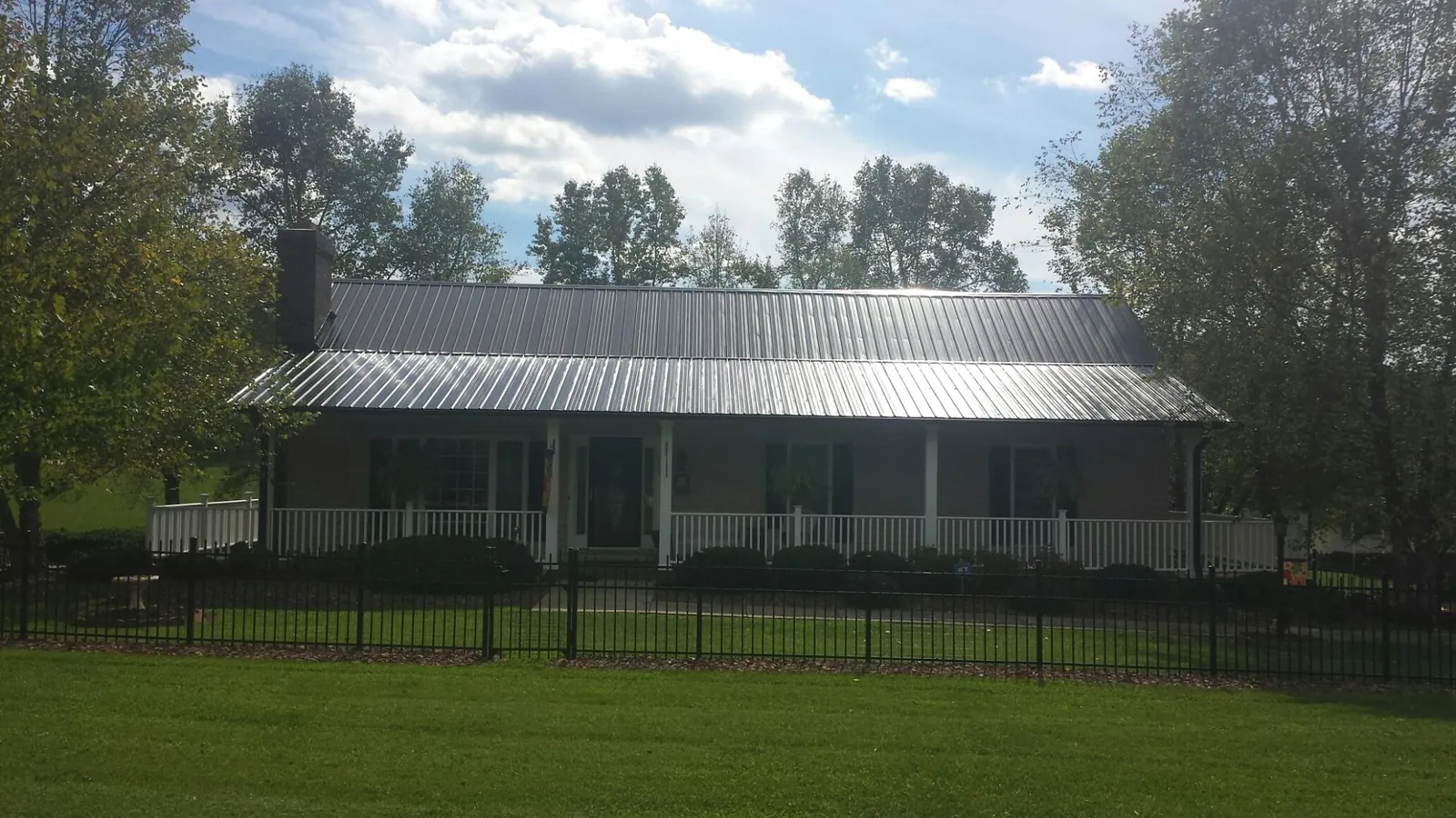 Gray metal roof on a brick ranch with a full width front porch — Gutter Guard Installation work by our crew in Pelion